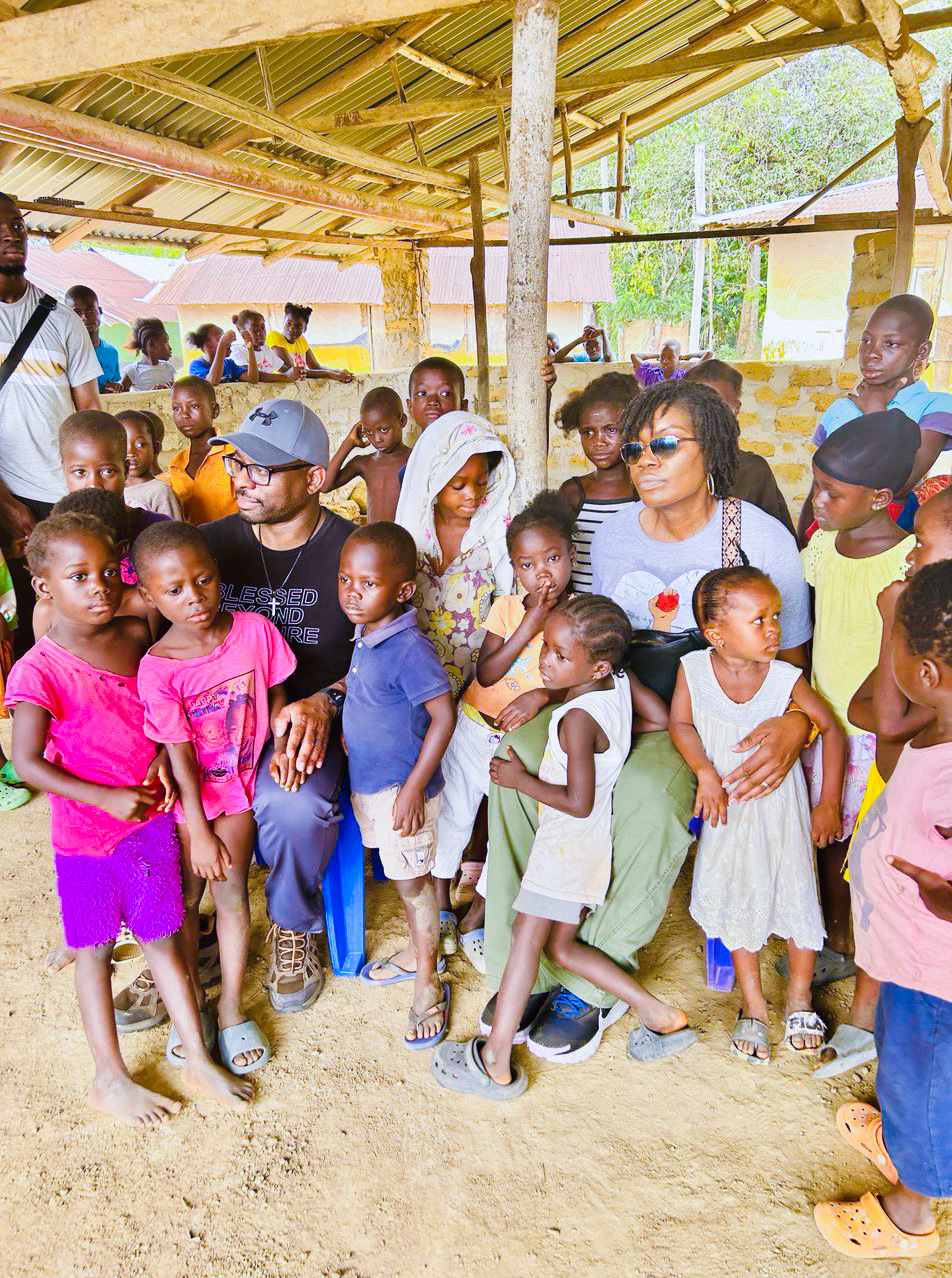 Albertina and Alastair Nyantee standing with a group of children during a KRN village outreach visit in Liberia